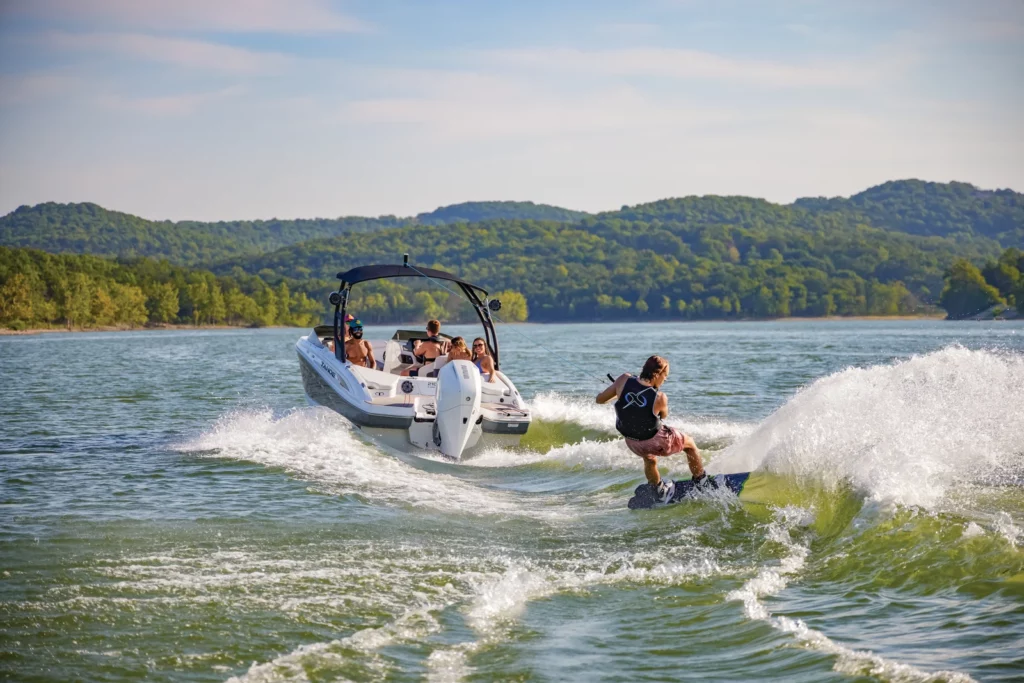 Tahoe power boat towing a wakeboarder on a scenic lake, showcasing Tahoe boats for watersports at Grand Pointe Marina