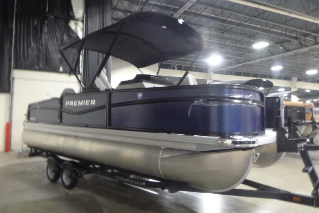 2026 Premier 210 SunSation Angler pontoon boat with bimini top on trailer displayed indoors