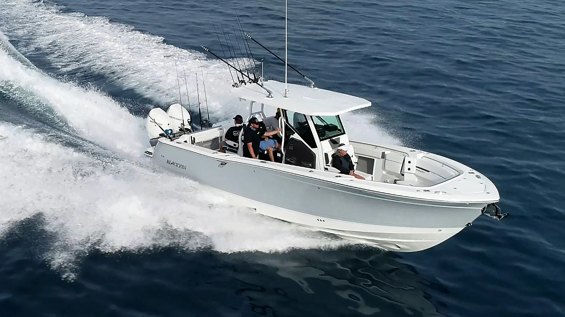 Center console fishing boat cruising at speed on open water with anglers onboard