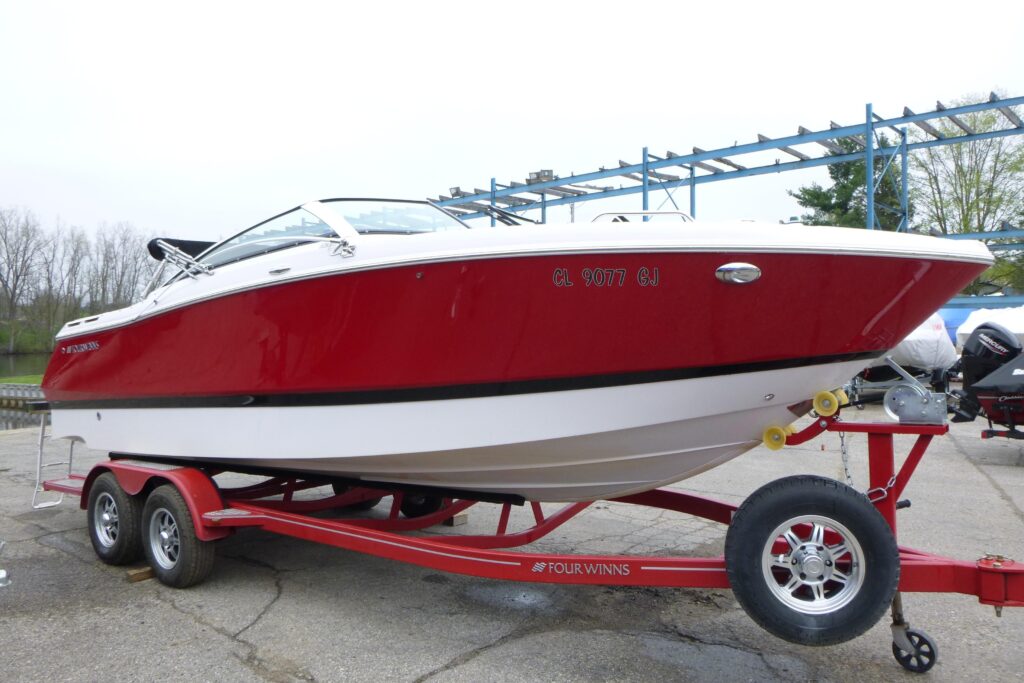2017 Four Winns H260 bowrider boat in red and white on trailer at Grand Pointe Marina dealership lot