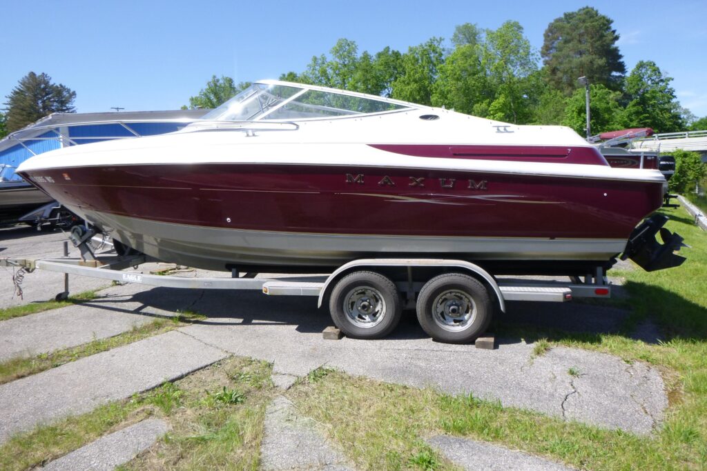 1998 Maxum 2300 SC power boat with burgundy hull, white deck, windshield, and tandem axle trailer.