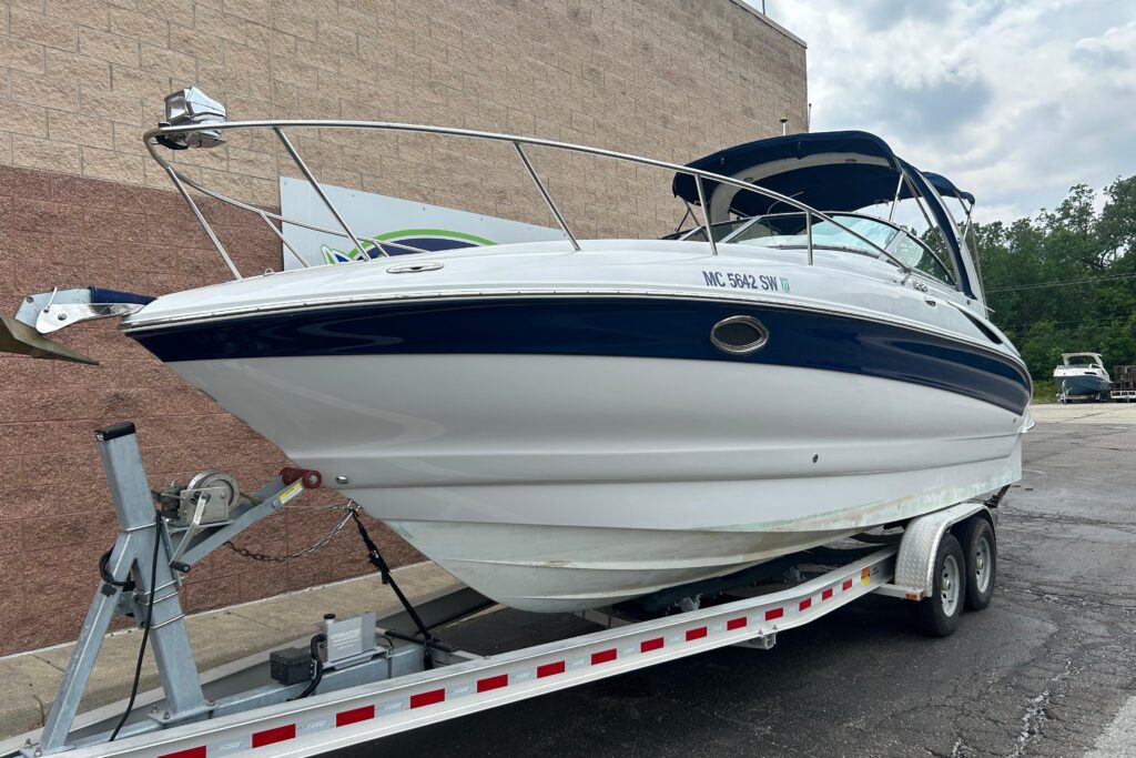 2006 Crownline 270 CR cruiser boat on trailer with white hull, navy stripe, and bimini top