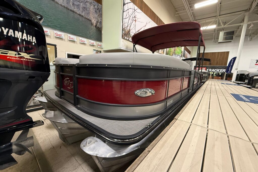 2022 Manitou 25 Encore pontoon boat with red exterior panels, bimini top, and Yamaha outboard motor