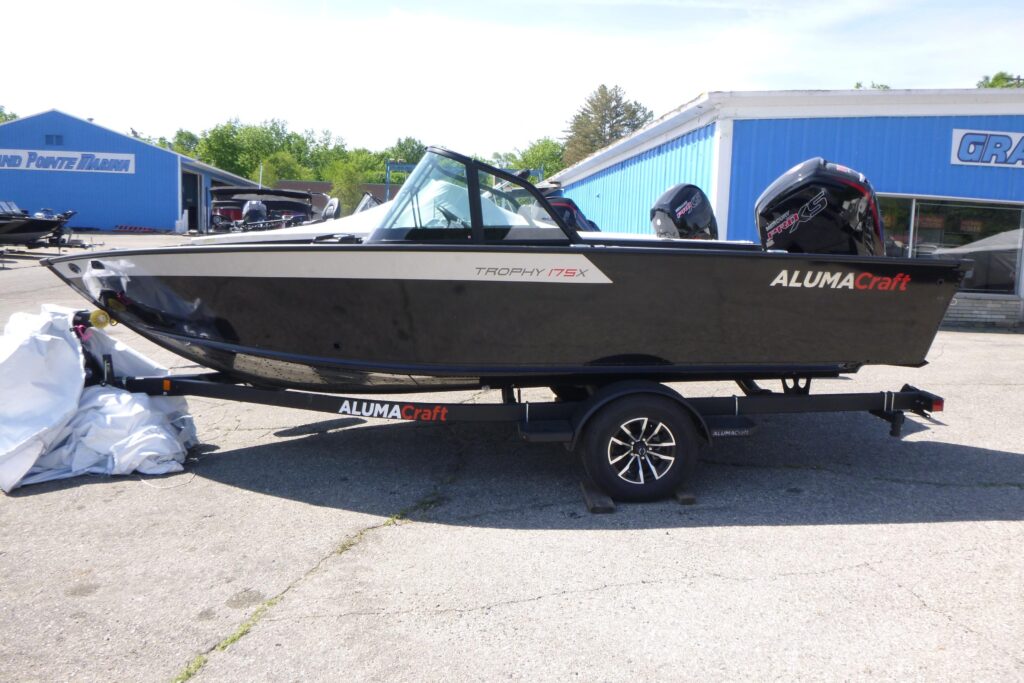 2025 Alumacraft Trophy 175X Sport fishing boat on trailer with dark hull, windshield, and Mercury outboard motors